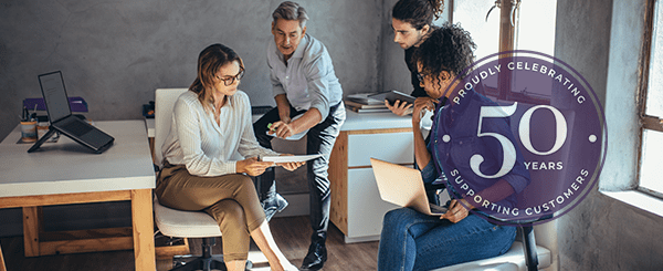 A group of four people in an office setting chatting.