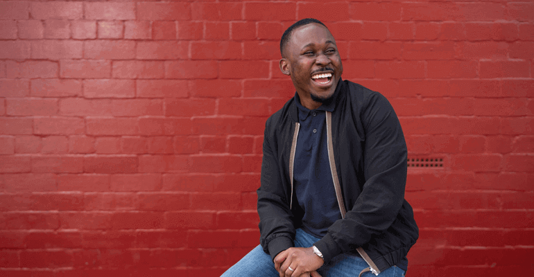 Man sat on a wall in front of painted red wall 820x550