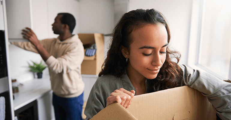 A couple emptying boxes in a kitchen.