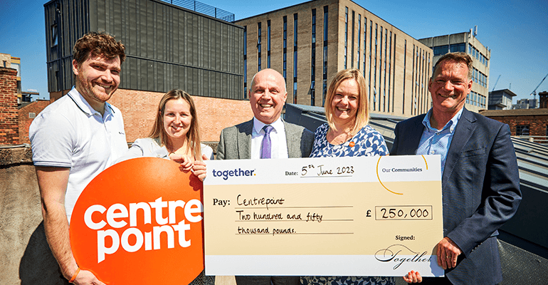 A group of Togethers employees smiling whilst holding a check for centrepoint.