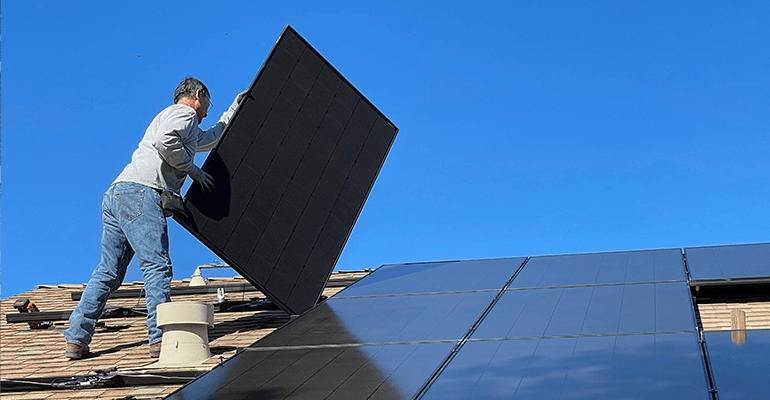 A man placing solar panels down on a roof.