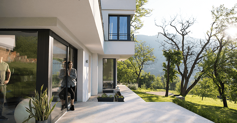 A modern home with a large garden and two people looking out.