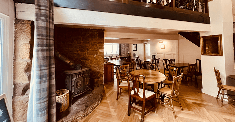 A pub with wooden chairs and tables out.