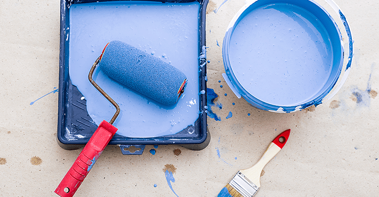 Blue painting equipment all together in front of a beige background.