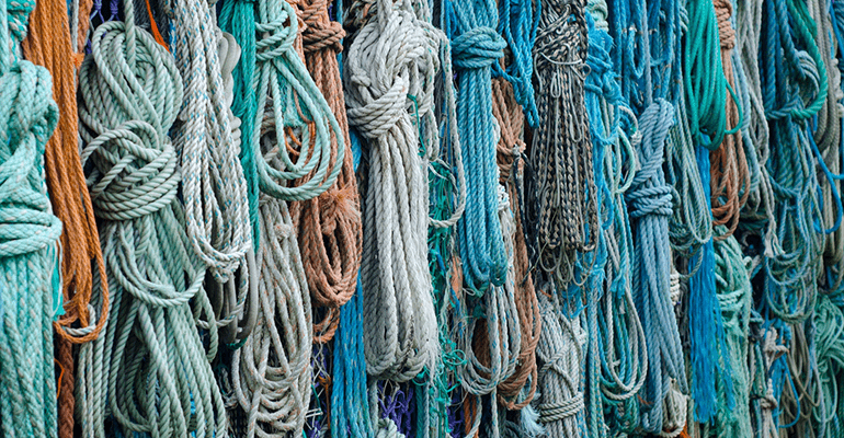 coloured and knotted ropes hanging on a wall - l