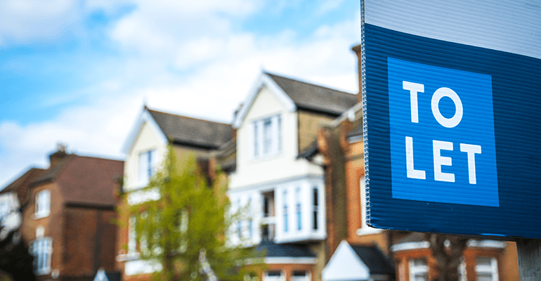 Estate agency To Let sign board with large typical British houses in the background  l