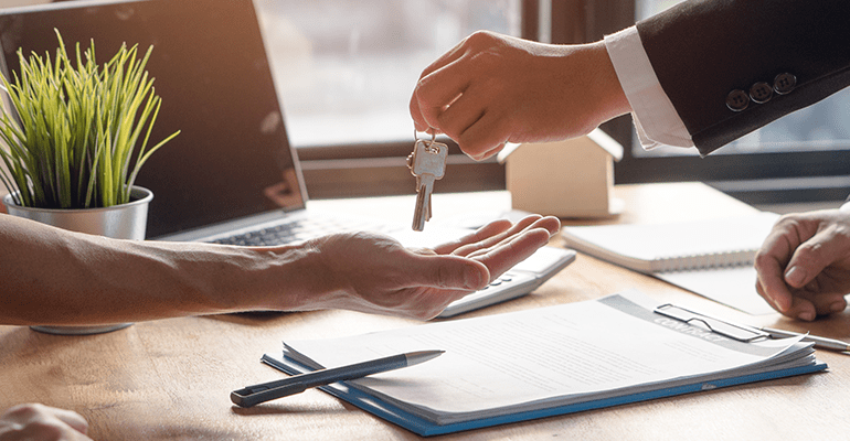 estate agent giving a key of property to new owner after signed agreement - l