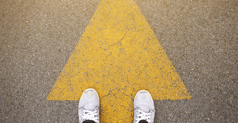 feet standing on a yellow arrow - l