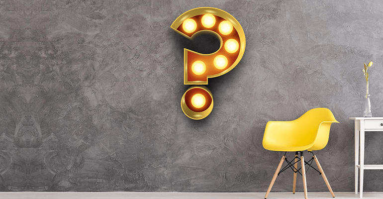 grey wall with lit up large question mark and a yellow chair - l