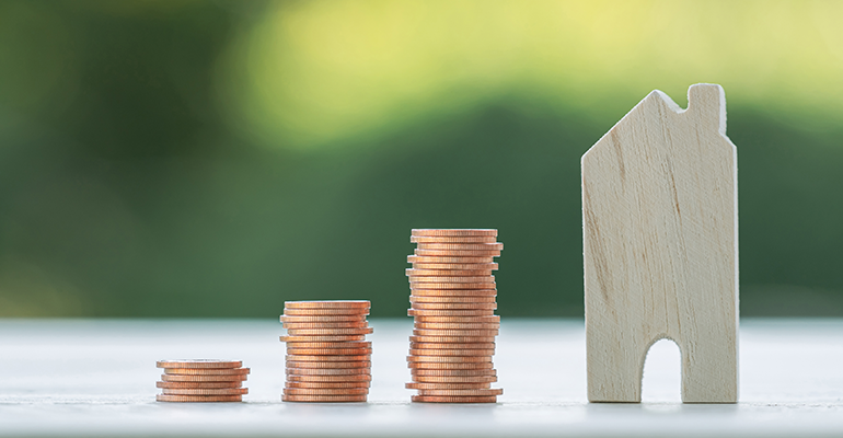 growing piles of coins next to a model house on a wooden table - l