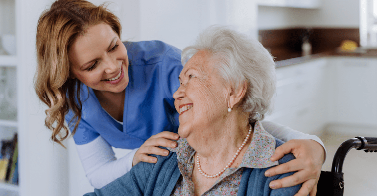 Happy elderly woman smiling at young female nurse.