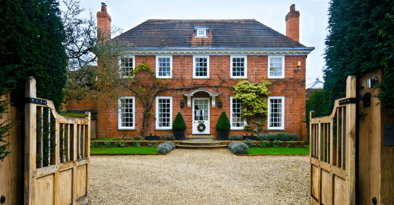 Large English country house with open wooden gates.