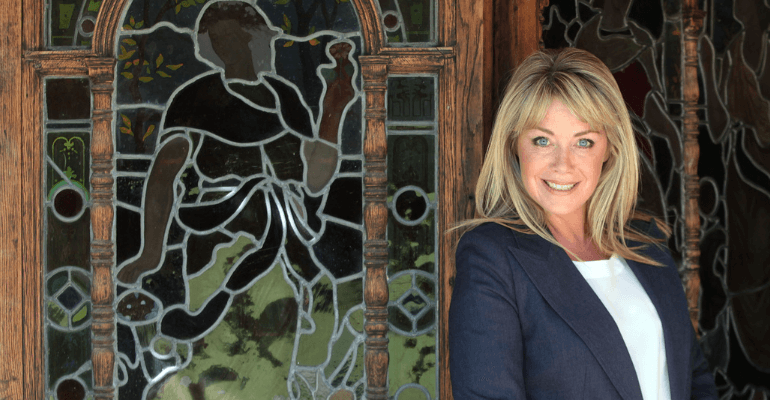 Lucy Alexander standing next to decorative door.