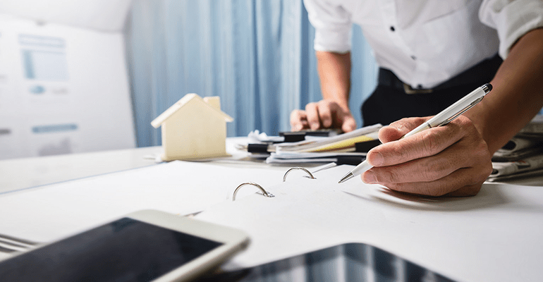 man holding a pen to an open file of papers - l