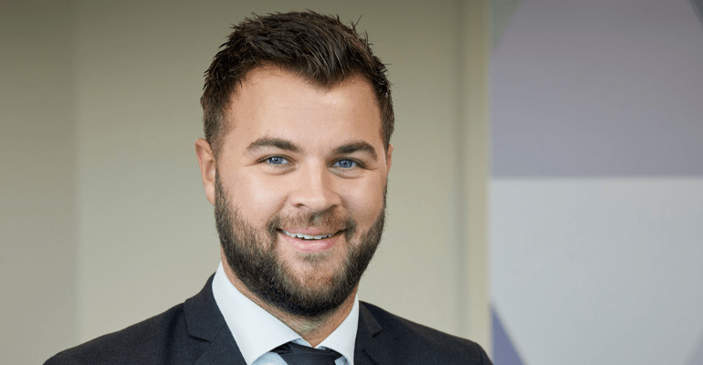 Man smiling in grey suit.