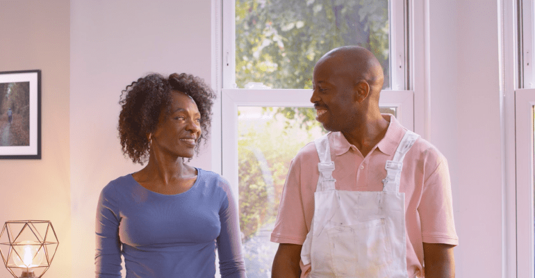 Middle aged couple looking at each other with decorating clothes on.