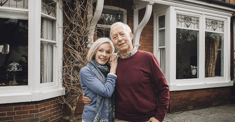 older couple stood together outside the front of a house - l