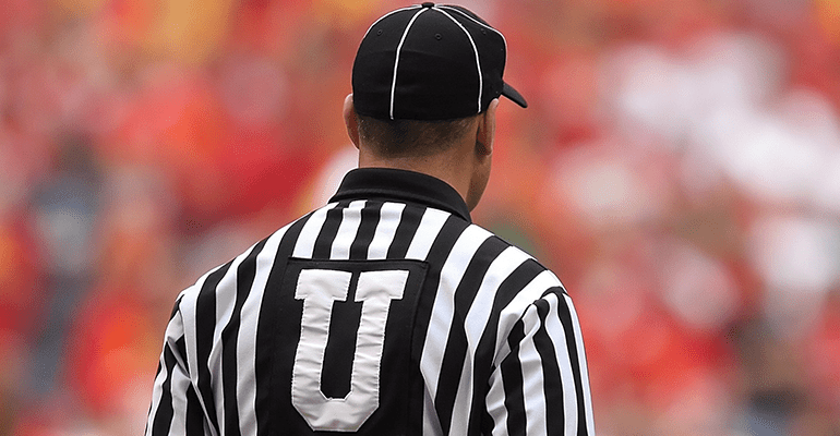 referee wearing a white and black striped top and a black cap - l