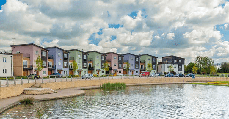 row of coloured houses next to a pond - l