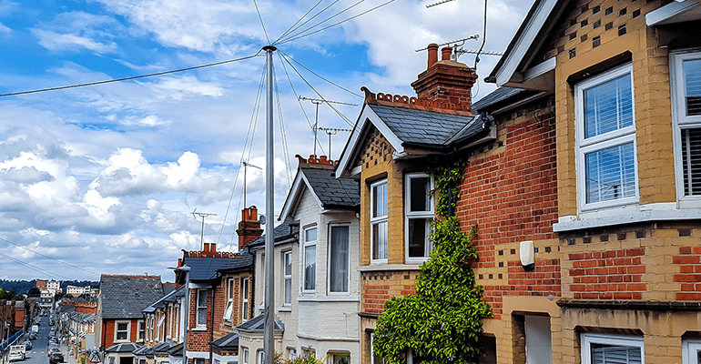 row of different brick coloured houses looking down a street - l