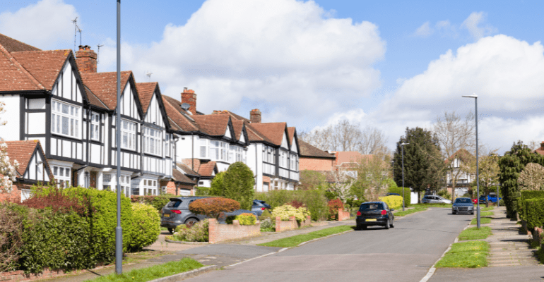 Row of traditional white and black Tudor style houses on a suburban UK road.