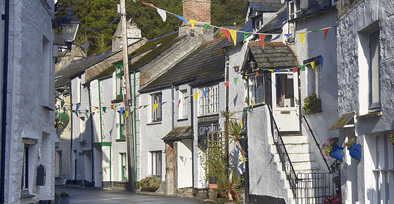 street of older white houses with bunting across the buildings - l