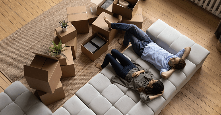 Top view happy couple tenants homeowners relaxing on couch on moving day - l