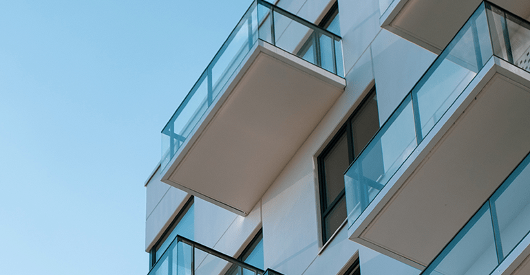 view looking up the side of a building with white balconies - l