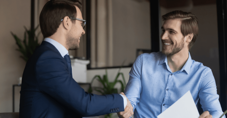 Young male broker and businessman happily shake hands.