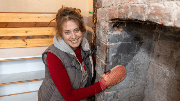 Smiling female renovating stone fireplace.