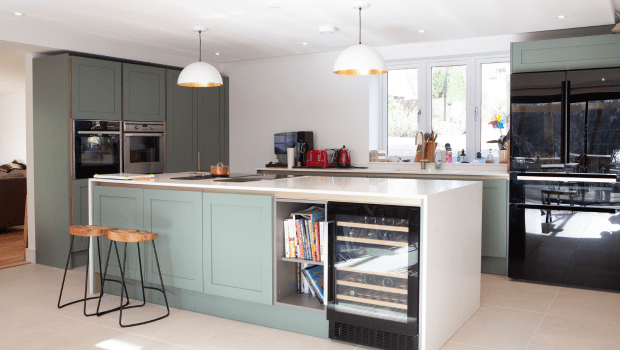 Stylish light green kitchen with counter surface in the middle.