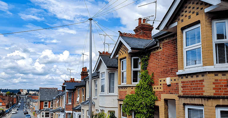 downhill view of a street of terraced houses and blue sky - l