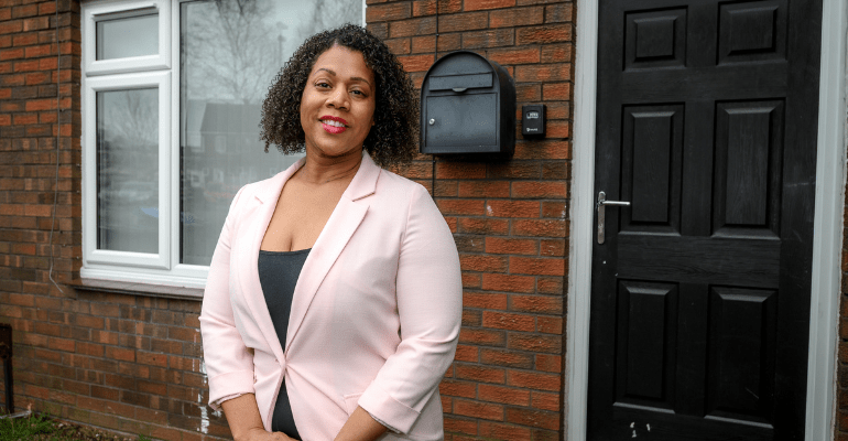 Female landlord standing in front of a house.