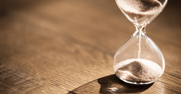 hourglass timer with sand passing through on a wooden table - l