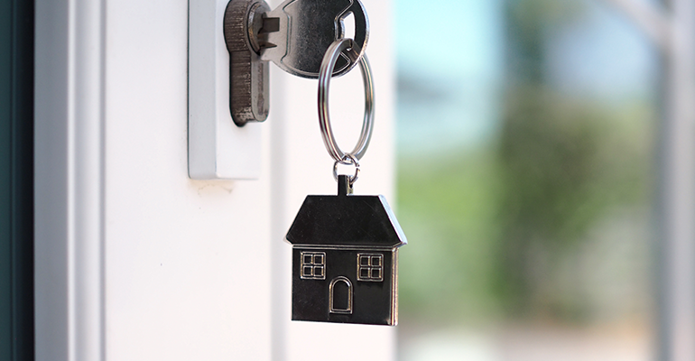 house key on a house shaped keyring in the keyhole for unlocking a new house - l