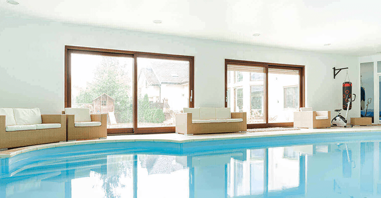 indoor swimming pool in a house with sofas around the edge - l