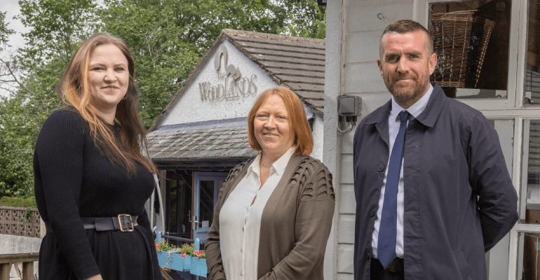 Man and two women smiling outside a building.