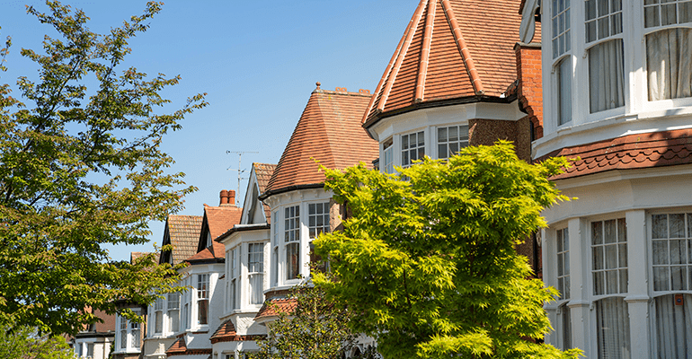 street with white houses with white bay windows lined with trees - l