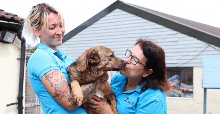 Two women holding a dog.