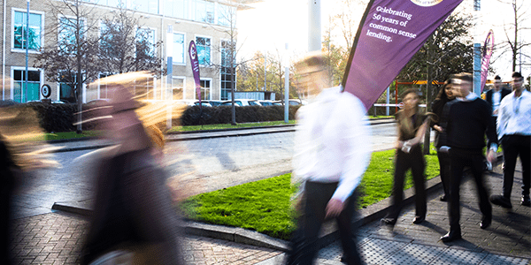 A wide shot of people walking into an office.