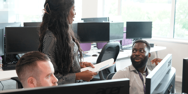 Colleagues talking at a desk - l