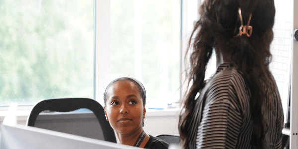 Two colleagues discussing work at a desk - l