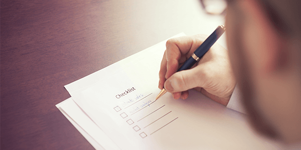 A close up of a man writing a checklist.