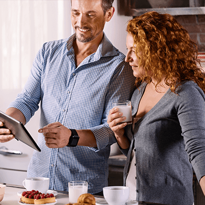 A couple standing together smiling looking at a phone.