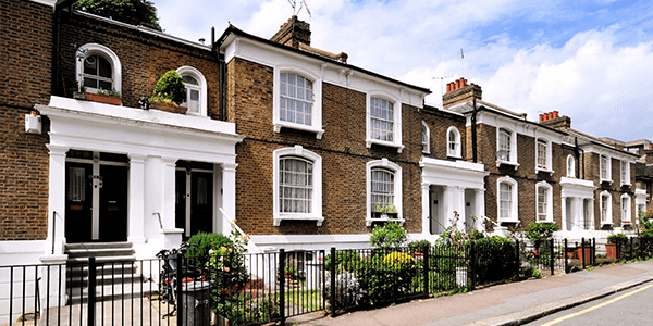 A wide shot of terraced houses with small front gardens on a street.