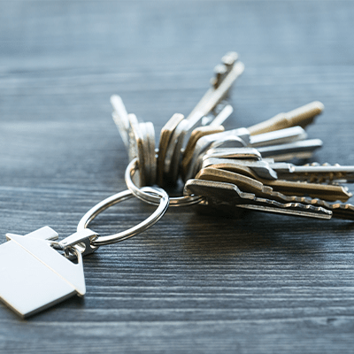 bunch of keys with house shaped key ring on a rustic wooden table - l