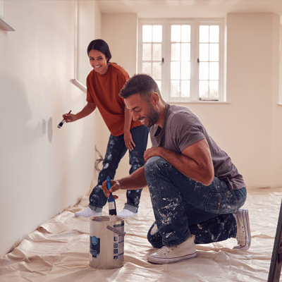 Couple Painting Test Squares On Wall As They Decorate Room In New Home Together - l