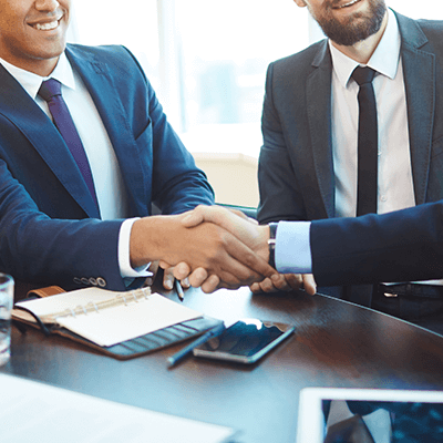 A group of three men with two shaking hands.