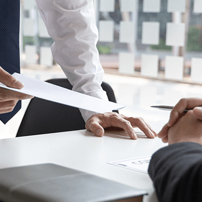 A close up of a man passing a document over to another man.