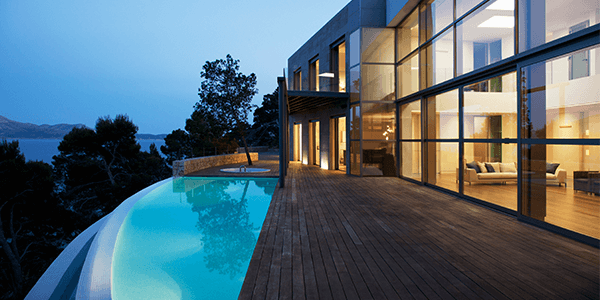 A house on the edge of a hill with an infinity pool outside.